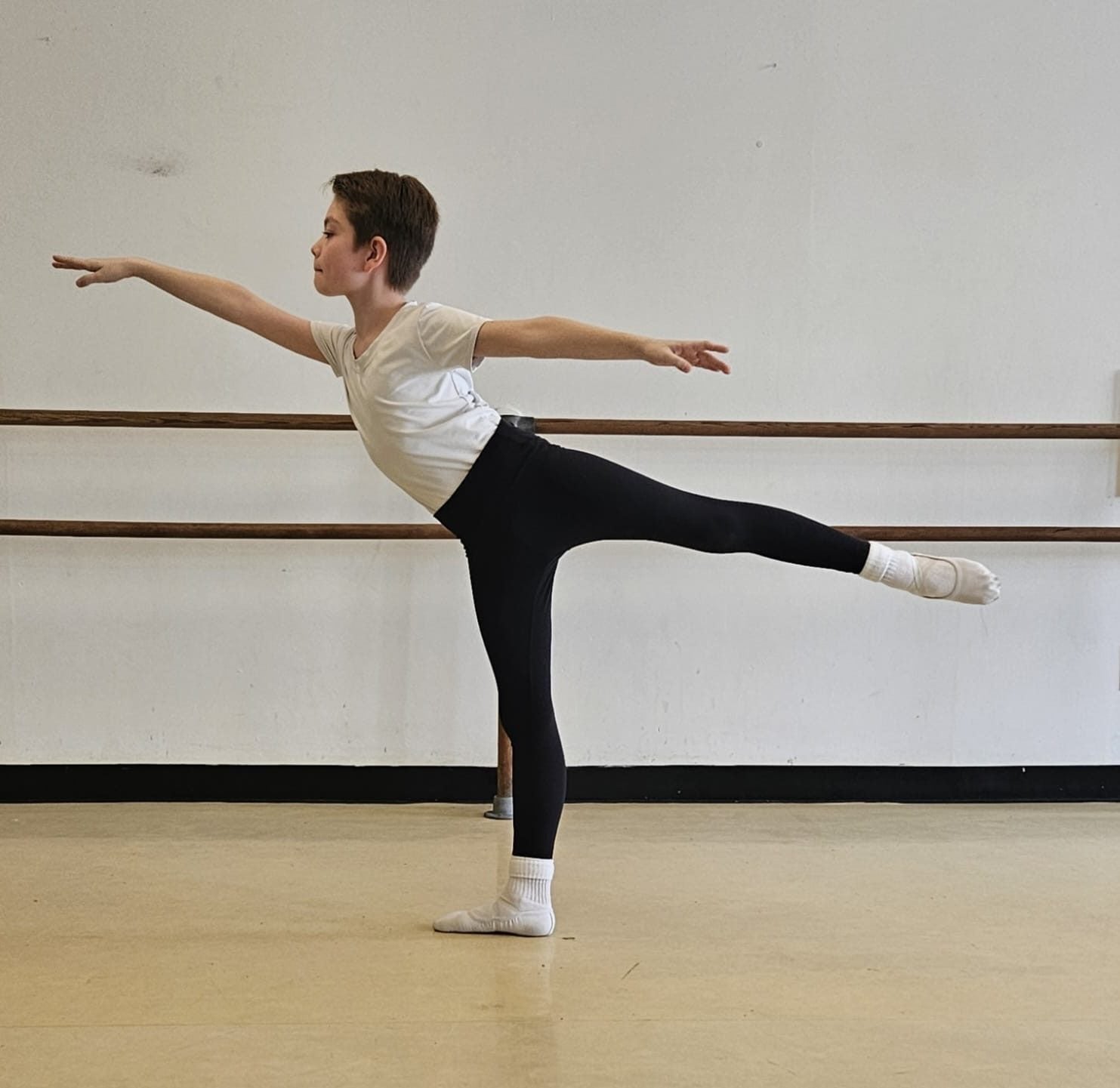 Young ballet dancer extending in arabesque during training